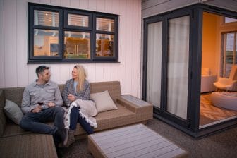 Couple sat on outdoor corner sofa on the lodge decking